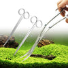Eine Hand hält ein Edelstahl-Aquarienset mit scharfen Scheren über grünen Moos.