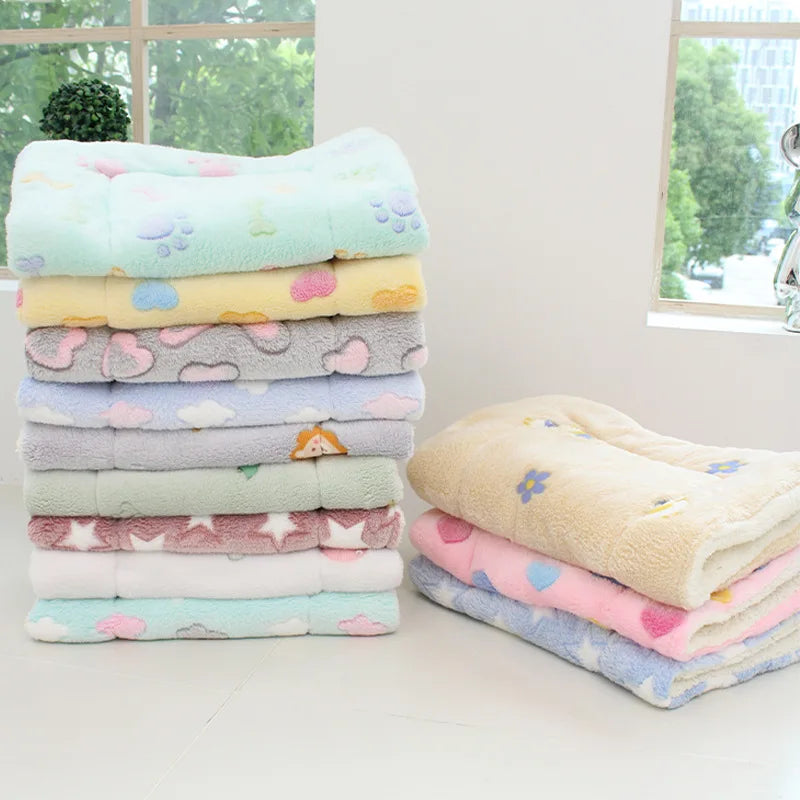 A stack of colorful plush fleece blankets and pet mats for dogs and cats in various pastel colors.
