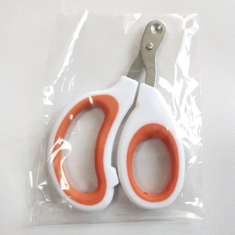 A pair of white adjustable pet nail clippers with orange grips are sealed in a clear plastic bag.