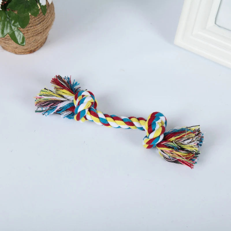 A colorful braided hemp rope chew toy for dogs with frayed ends, lying on a white surface.