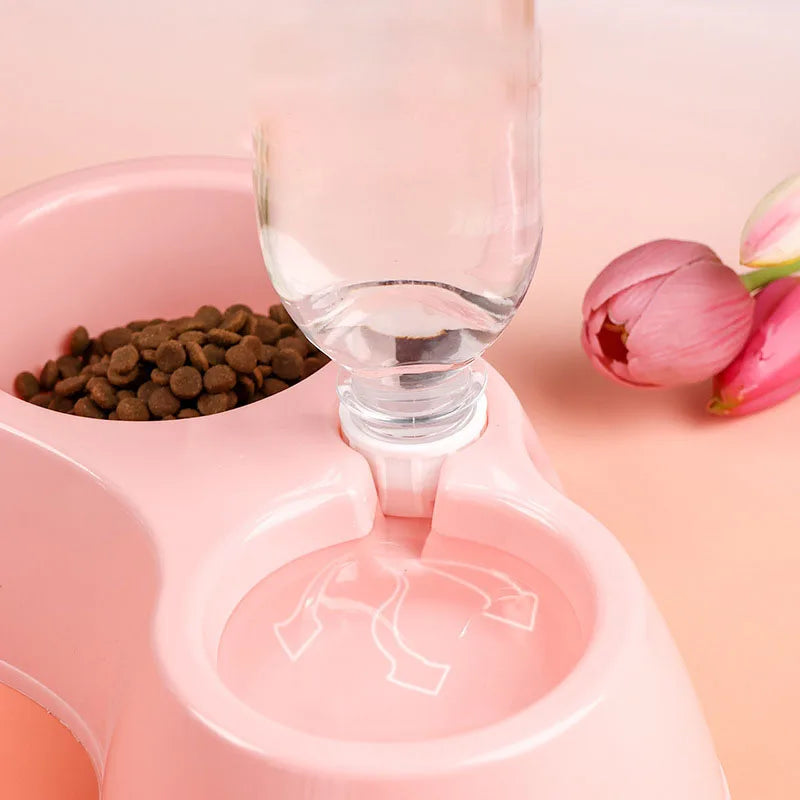 A pink dual-bowl feeder for cats and dogs is shown with food and water being dispensed.