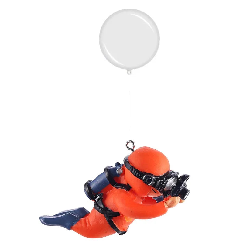 An orange resin mini diver aquarium ornament with black gear is suspended by a clear plastic dome.