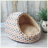 A round, beige and blue patterned pet bed shaped like a cave for small and medium dogs.