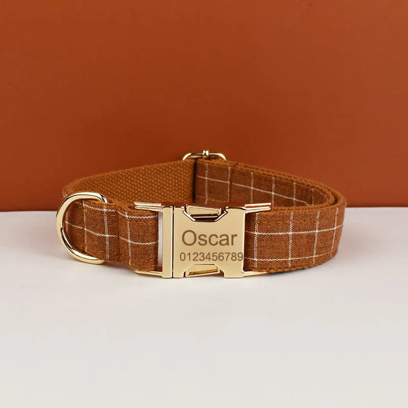 A brown plaid dog collar with a gold buckle and the name Oscar engraved on the tag.