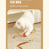 A white kitten plays with a set of three feather elastic balls on a beige rug.