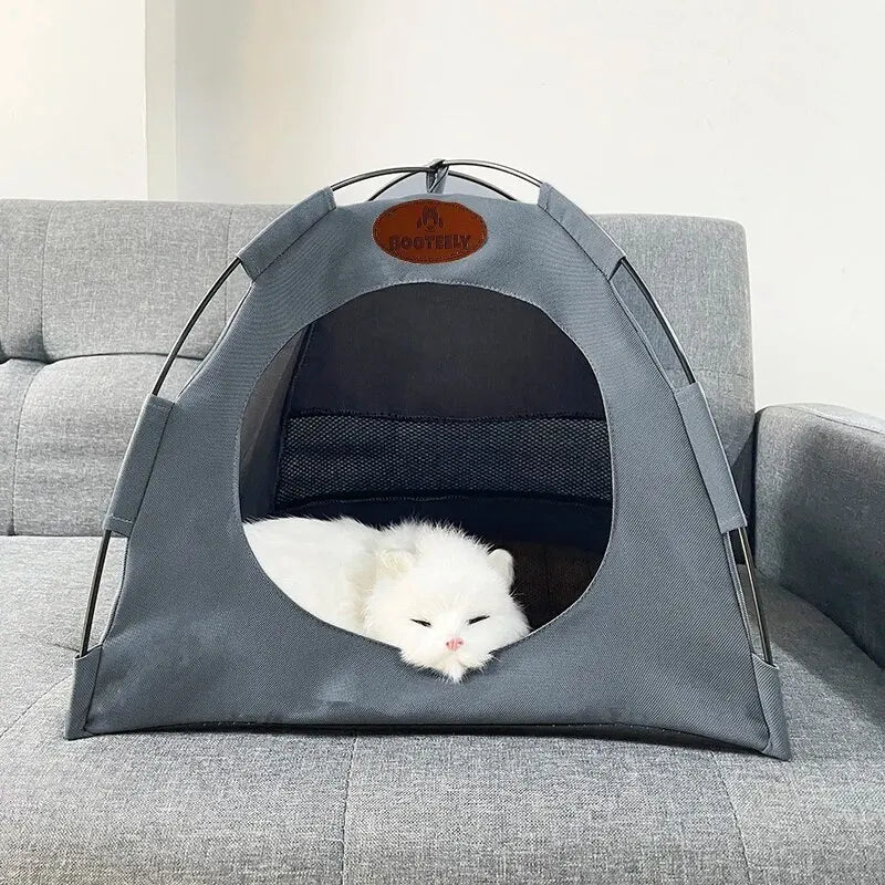 A gray foldable outdoor cat tent with an arched entrance is placed on a gray sofa.