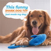 A golden retriever dog is lying down next to a blue shark chew toy.