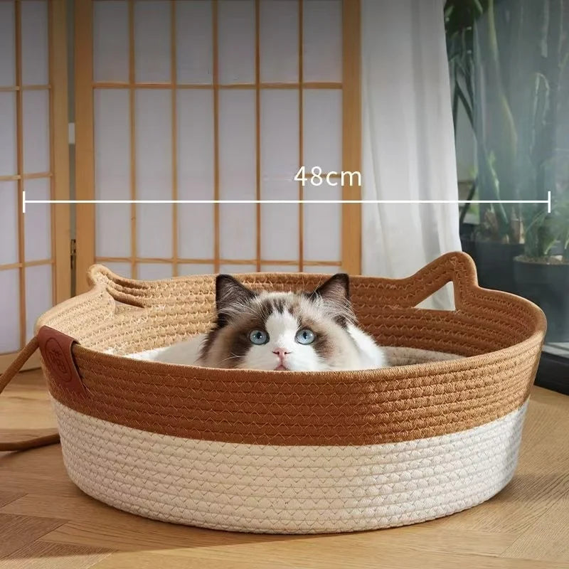 A handwoven rattan cat bed with a cotton rope edge is shown holding a fluffy gray and white cat.