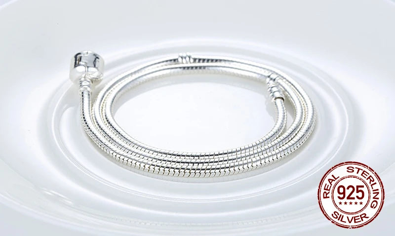 Sterling silver snake chain necklace with a heart charm displayed on a white plate.