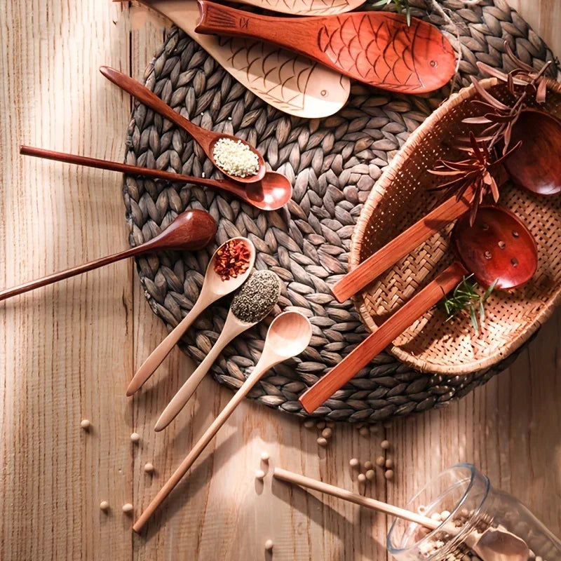 A collection of six wooden tea and coffee spoons arranged on a woven mat and wooden surface.