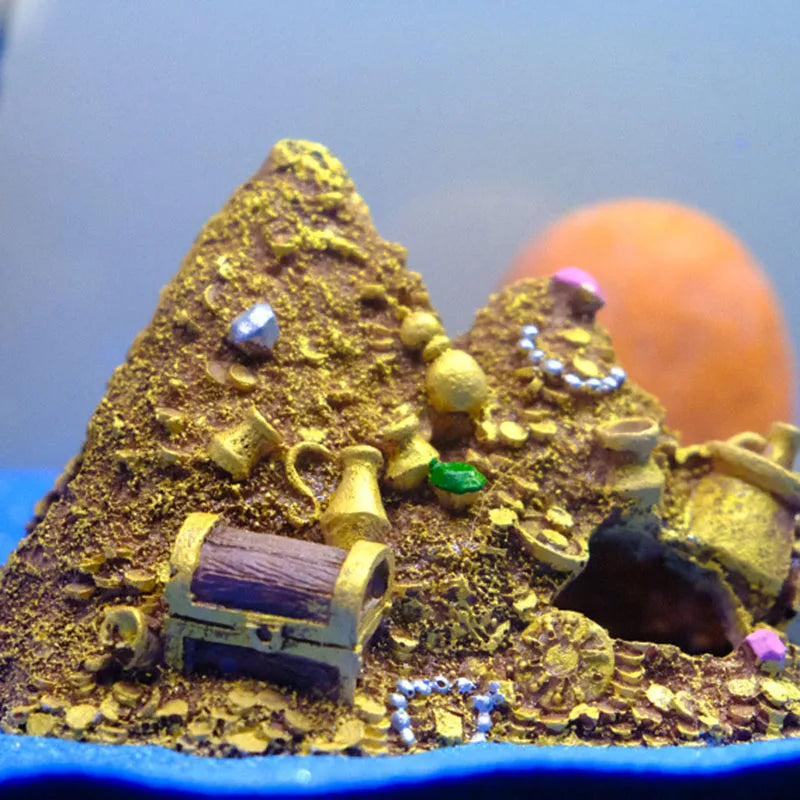 A miniature mountain cave hideout decoration featuring gold-colored terrain, treasure chests, and small gems.