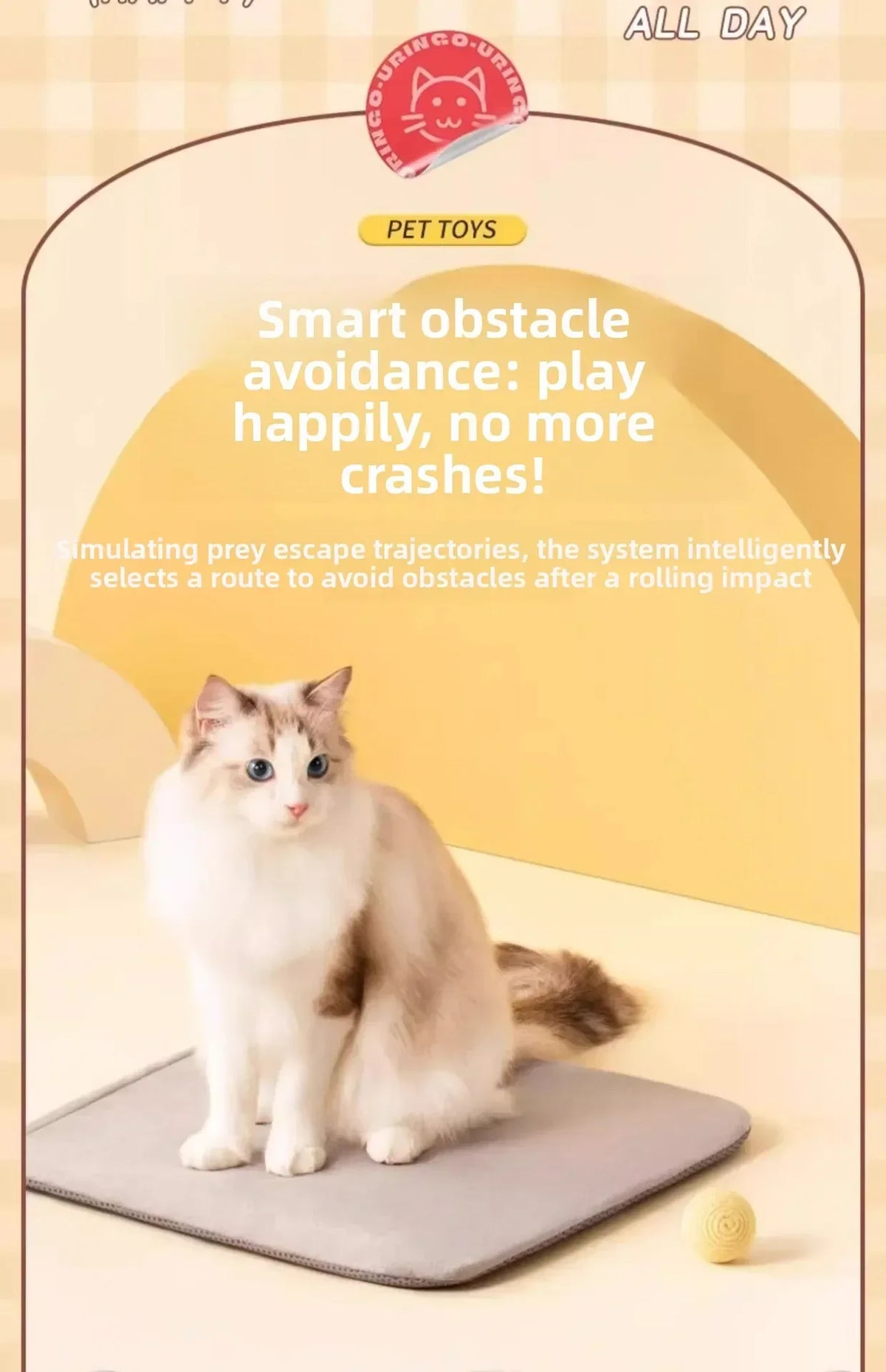 A fluffy white and brown cat is sitting on a gray mat next to a small yellow ball toy.