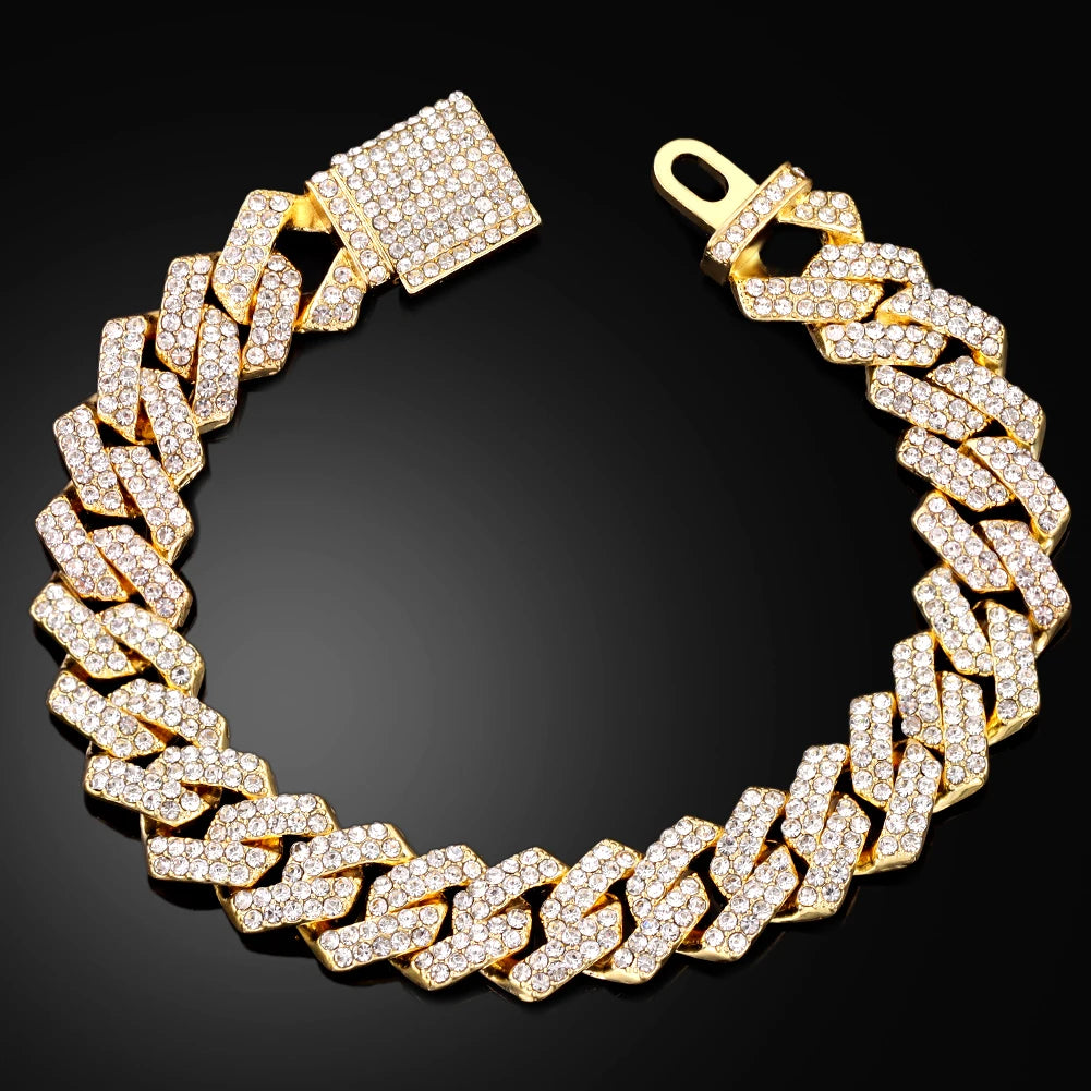 A gold iced-out Cuban link bracelet with rhinestone pavé set against a black background.
