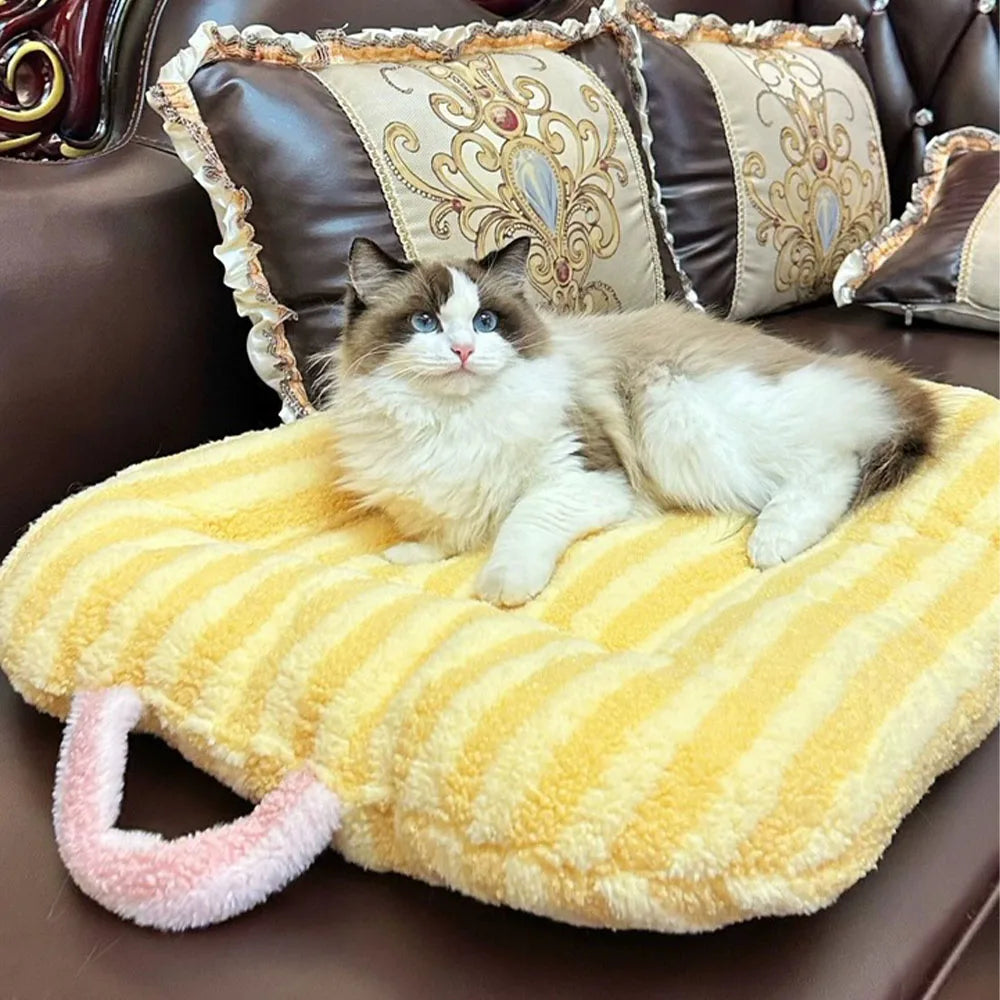 A fluffy brown and white cat is relaxing on a yellow plush oval pet bed.