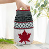 A knitted dog sweater featuring a red maple leaf design and gray geometric patterns.