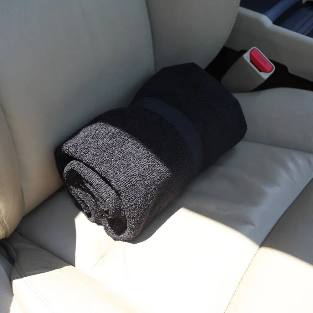 A dark gray waterproof non-slip car seat cover protector rolled up on a light gray fabric surface.