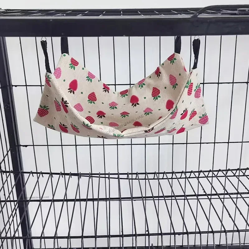 Columpio de hámster de dos capas y peluche con estampado floral colgando dentro de una jaula de alambre.