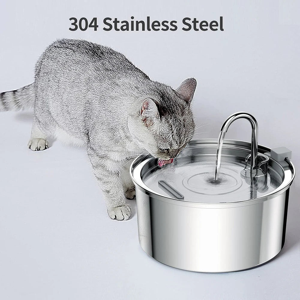 Un chat gris boit de l'eau dans une fontaine à eau en acier inoxydable.