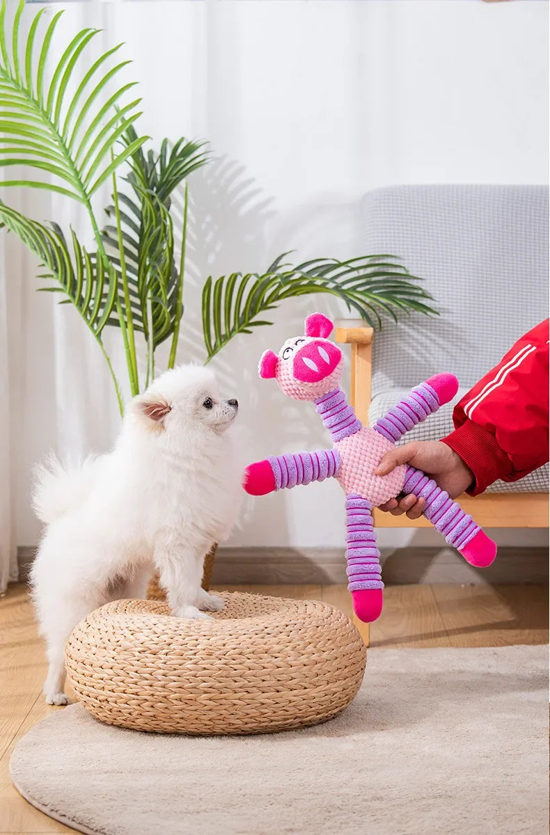 Ein weißer, flauschiger Hundespielzeug in Form eines rosa Pferdes wird von einer Hand gehalten und liegt auf einer geflochten