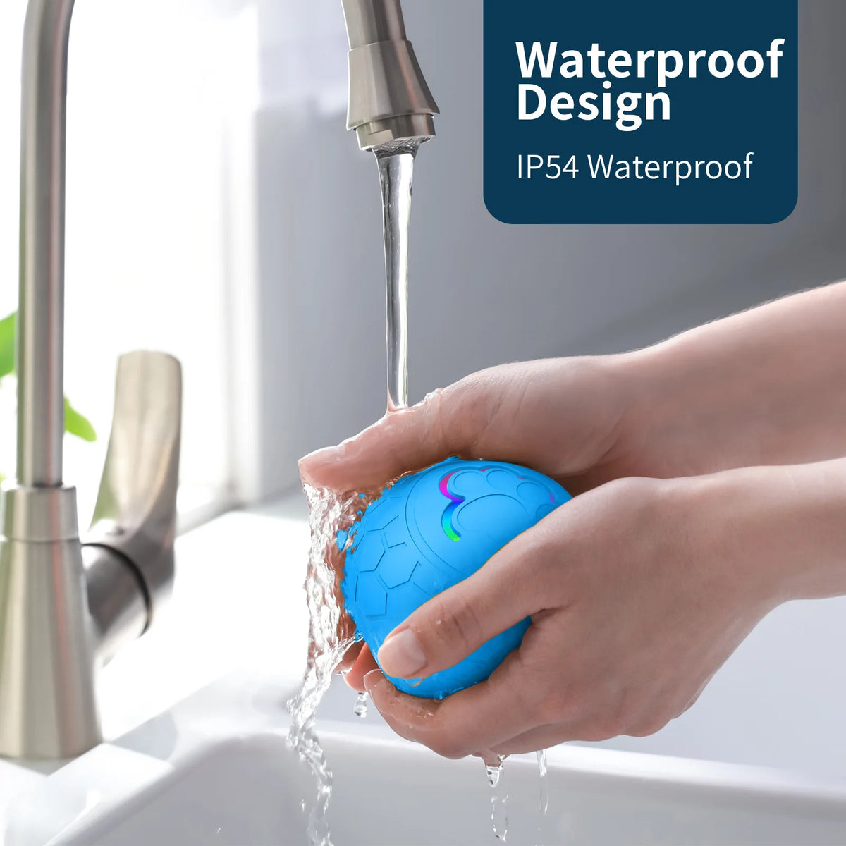 Eine Hand hält einen blauen interaktiven elektronischen Haustierball, während Wasser aus einem Wasserhahn darauf fließt.