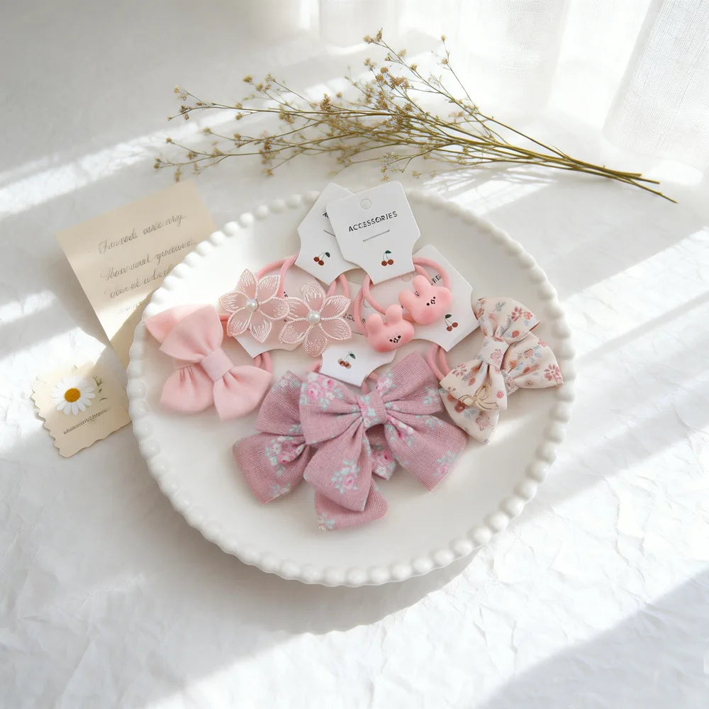 Présentation de nœuds pour cheveux élastiques roses et floraux avec des accessoires, disposés sur une assiette blanche avec d