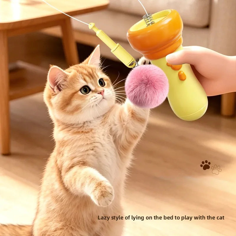 A hand is holding a yellow and orange electric wand toy, which a cat is batting at.
