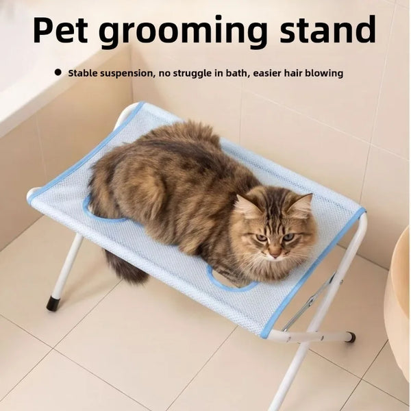 A fluffy tabby cat is resting on a blue mesh grooming stand for pet bathing.