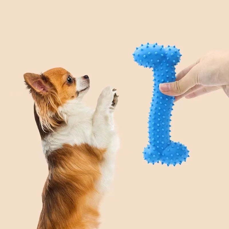 A hand holds a blue textured toy shaped like the number one, next to a dog.