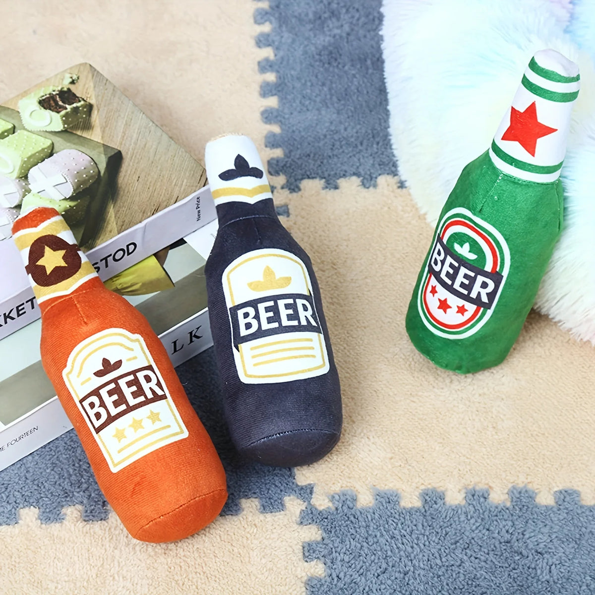 A funny beer bottle shaped squeaky dog toy in orange and dark blue colors resting on a fuzzy surface.