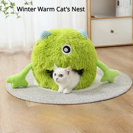 Nido de gato monstruo verde esponjoso con un gatito blanco asomándose, descansando en una alfombra gris antideslizante.