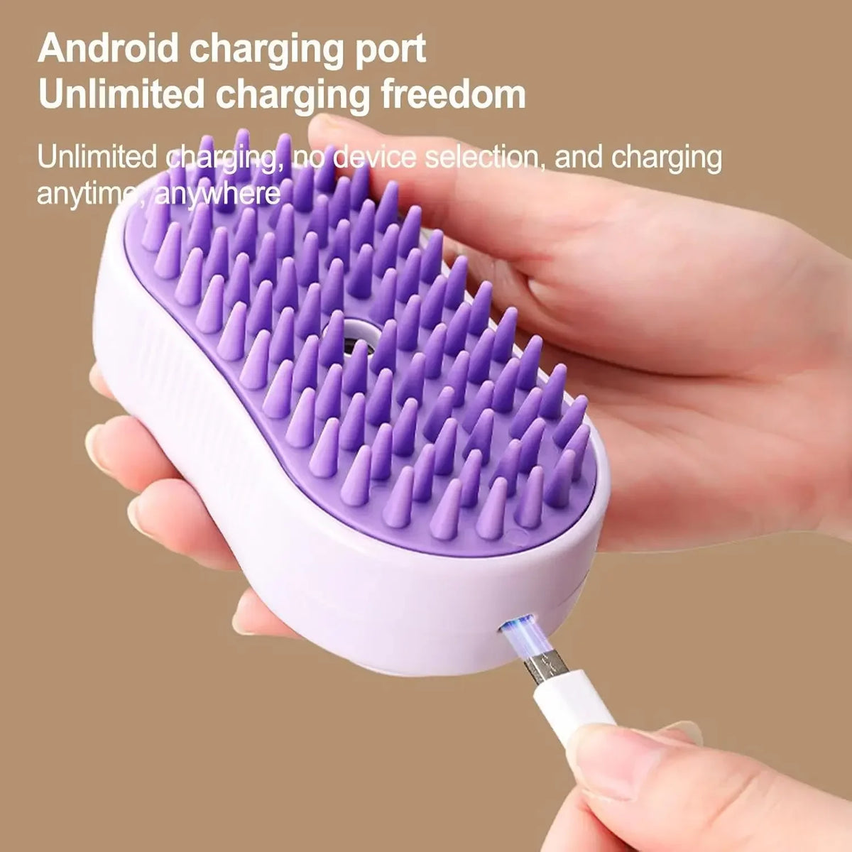 A hand holds a purple silicone cat grooming brush with soft massage bristles, demonstrating an Android charging port.