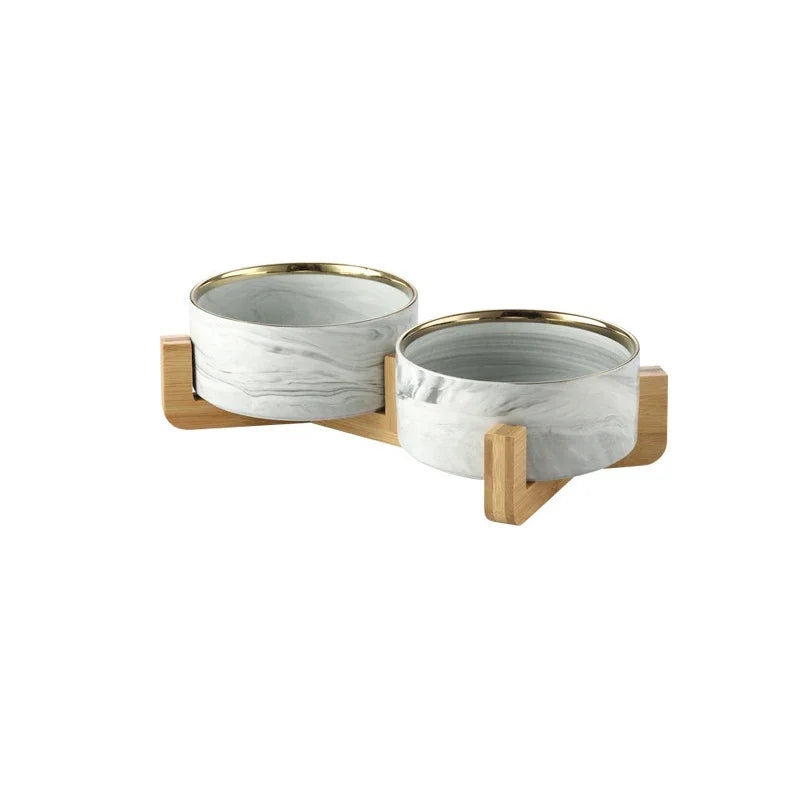 A set of two marbled ceramic pet bowls with a wooden stand.