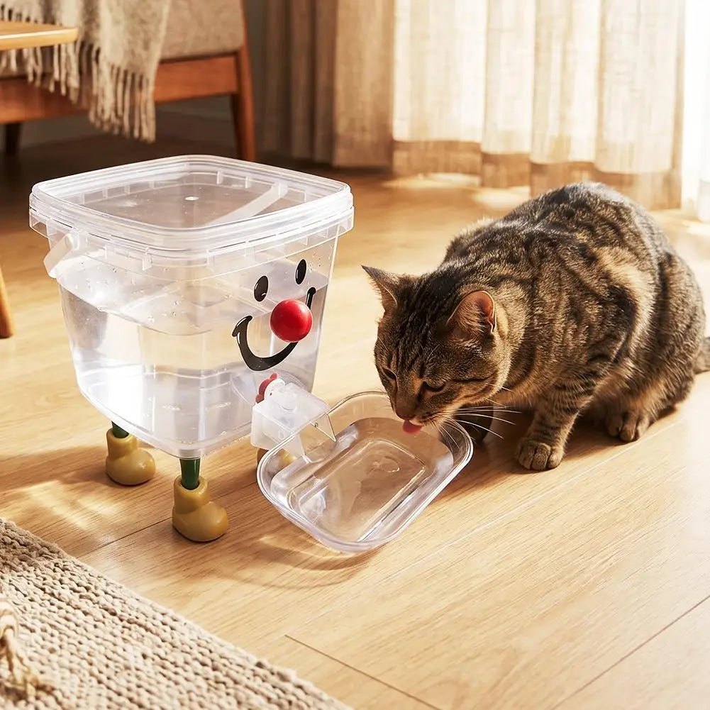 A tabby cat is drinking water from a clear plastic pet water fountain designed to look like a smiling face.
