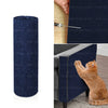 A dark blue self-adhesive cat scratcher pad rolled up, shown next to a hand and a piece of furniture.