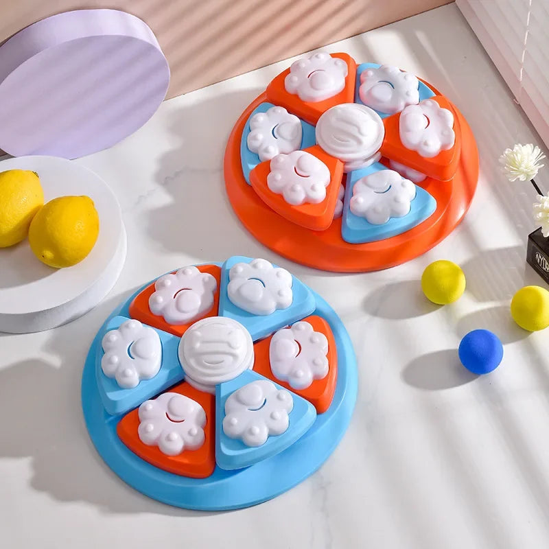 An orange puzzle feeder bowl for pets with white and blue food compartments, surrounded by yellow and blue balls.