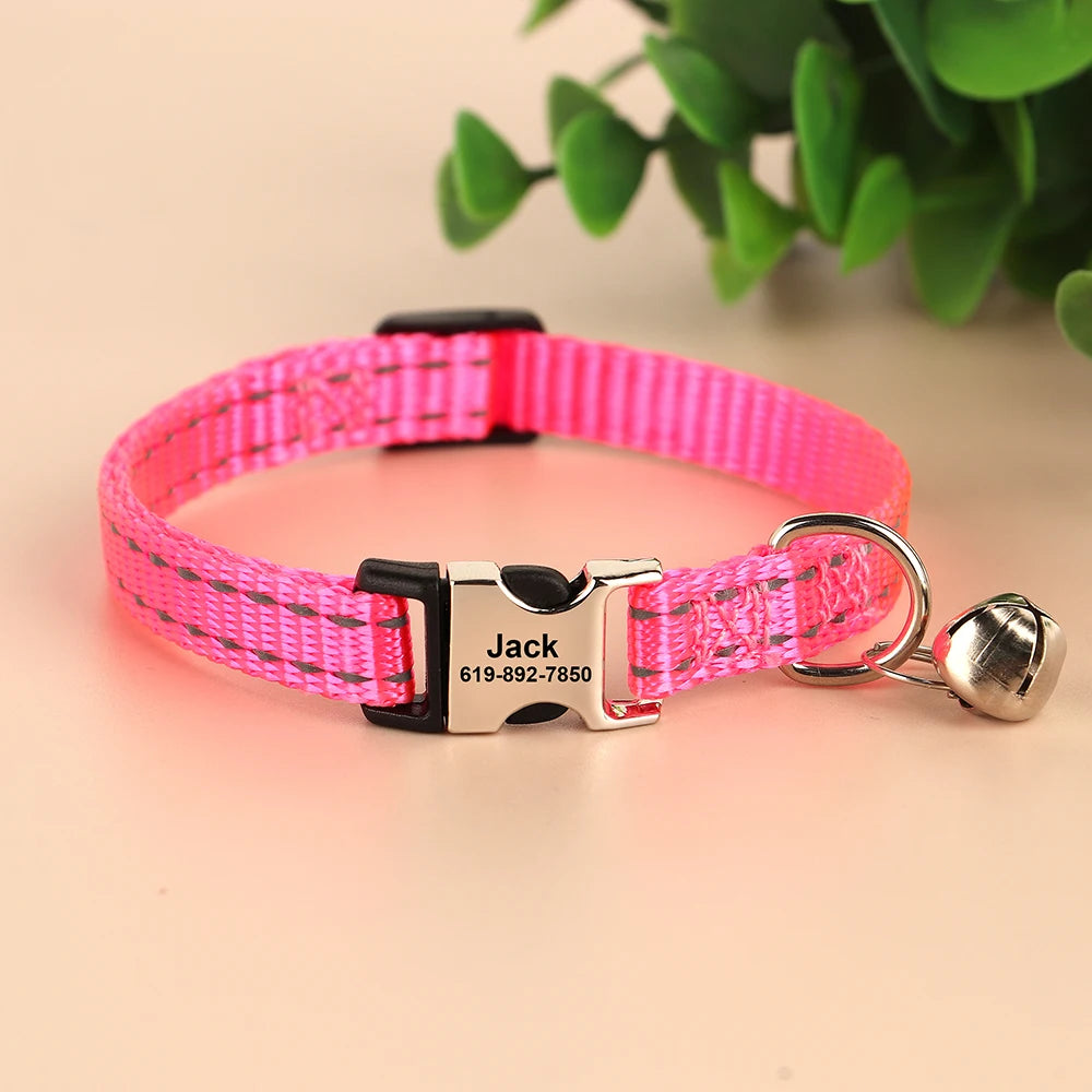 Pink reflective nylon cat collar with a black buckle and silver bell attached to an ID tag