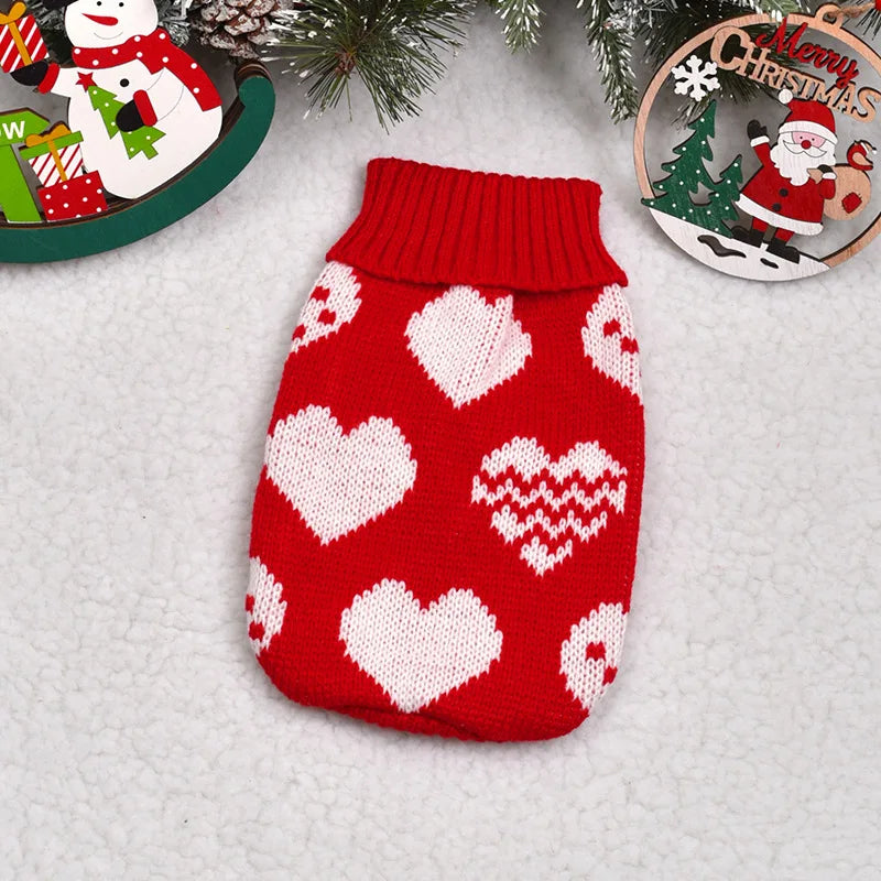 A knitted red sweater with white heart and geometric patterns, displayed on a white background.