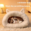 A fluffy white plush sleeping bag shaped like a cat's head, with a small tabby kitten resting inside.