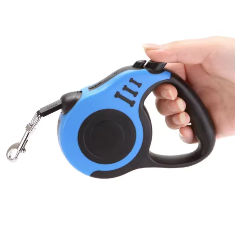 A hand is holding a blue and black automatic retractable dog leash.