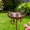 Stabile Garten-Vogelbad aus Eisen mit Wasser, ein Vogel trinkt aus der Schale in einem grünen Garten.