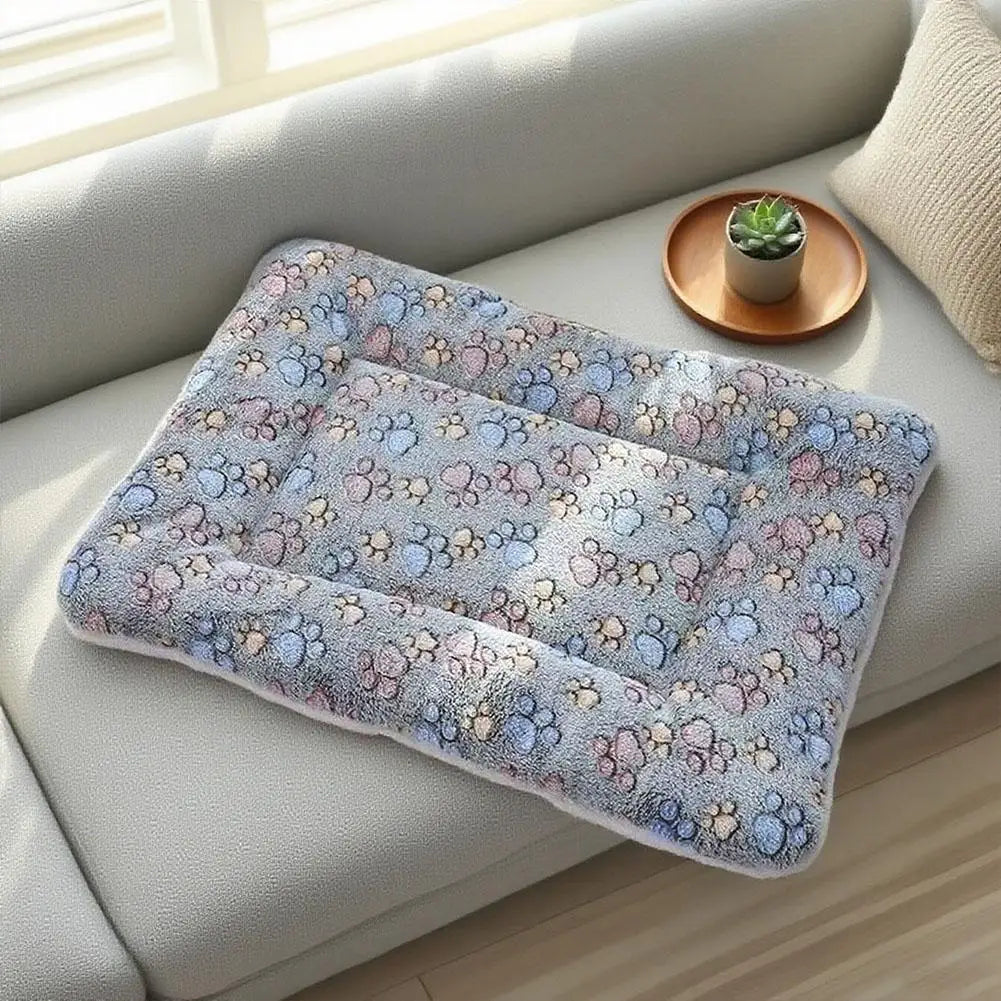 A plush double-sided pet blanket mat with a soft, textured pattern is placed on a light-colored sofa next to a small potted p