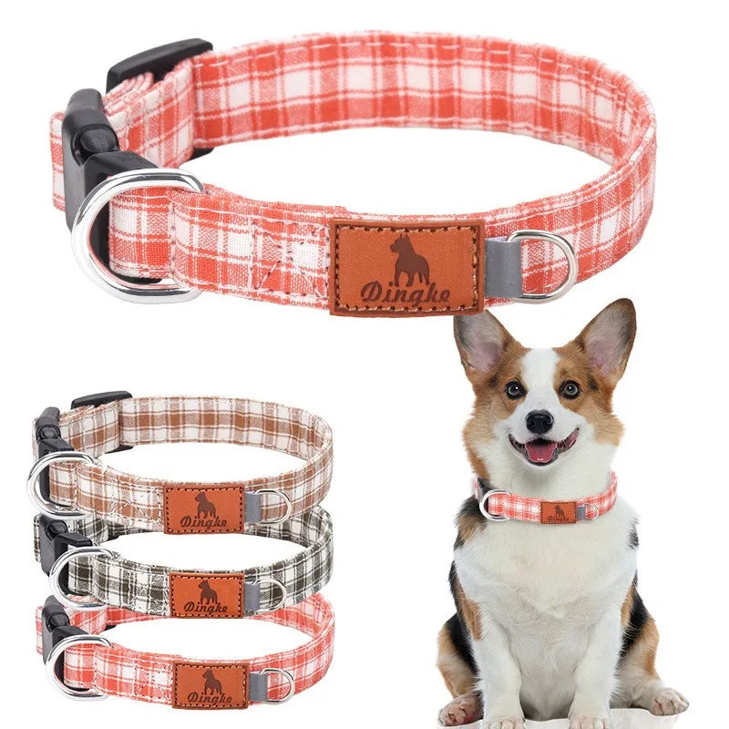 A red and white plaid polyester dog collar with a buckle and a leather tag, shown next to a small dog.