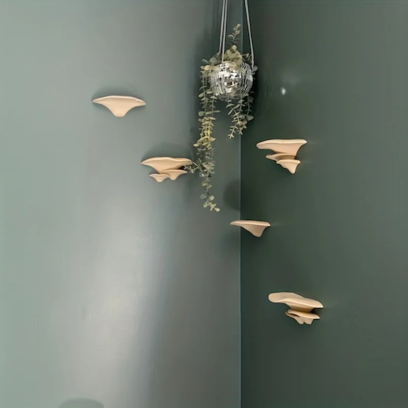 A decorative storage rack with mushroom-shaped pieces is mounted on a green wall.