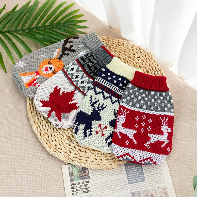A collection of knitted dog sweaters in various patterns and colors laid on a woven mat.