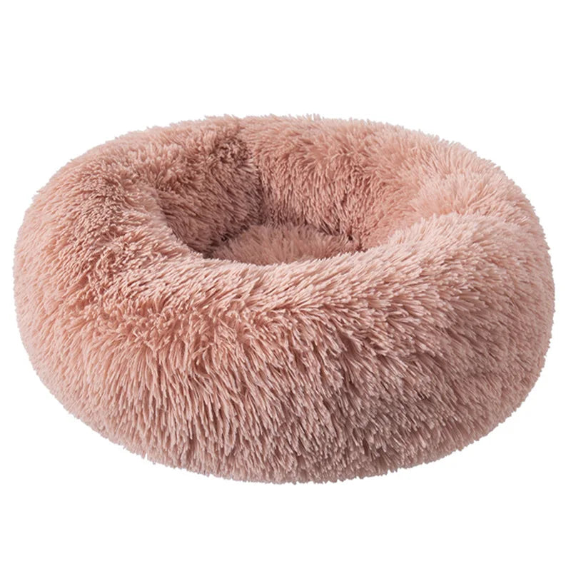 A plush, round pet bed with an anti-slip base covered in soft, light pink faux fur.