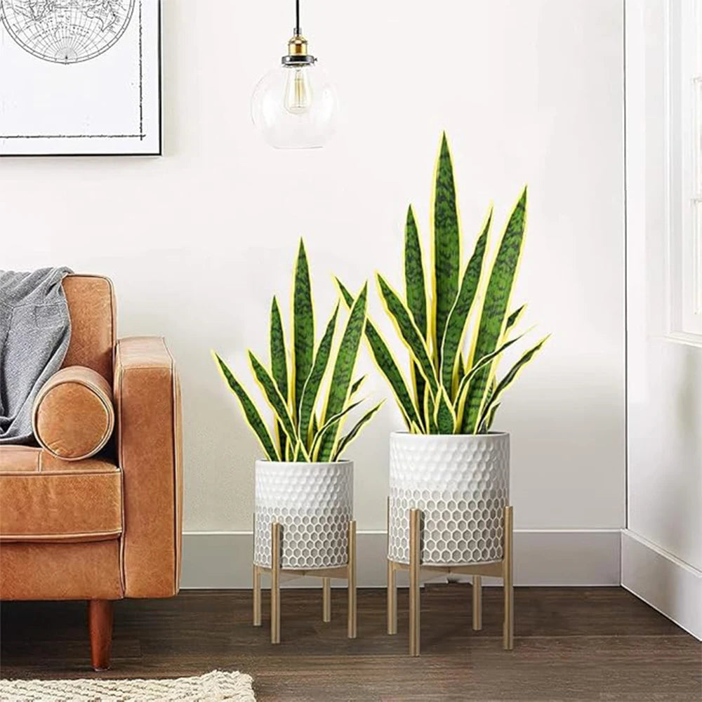 Artificial snake plant in a white textured pot displayed on a wooden floor.