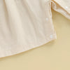 A light beige floral embroidery toddler romper for girls shown in a close-up view.