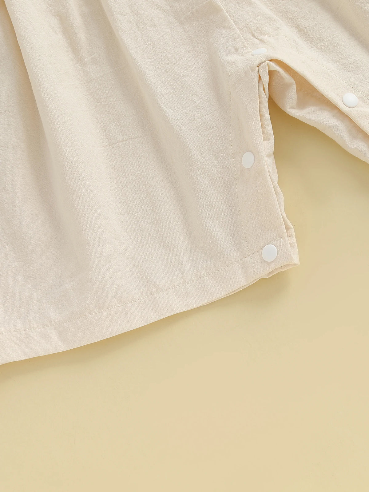 A light beige floral embroidery toddler romper for girls shown in a close-up view.