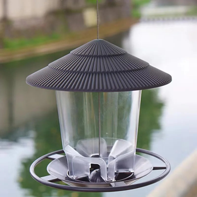 Mangeoire à graines pour oiseaux étanche avec bol en verre transparent et toit conique gris foncé, suspendue au-dessus de l'e