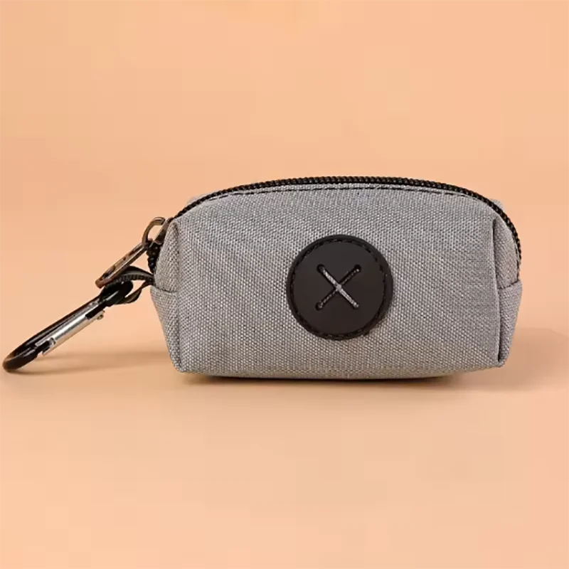 A gray zippered pouch with a black circular cross design and a metal clip.